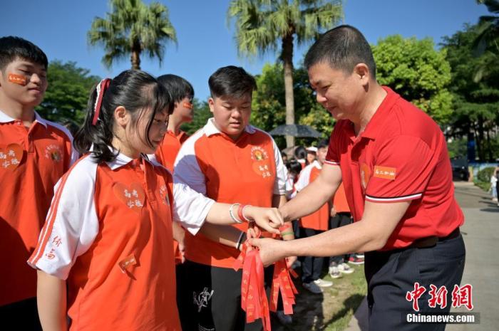 資料圖：廣西華僑實(shí)驗(yàn)高中的教師為高三學(xué)子系上紅絲帶，盼望學(xué)子高考必勝。 俞靖 攝